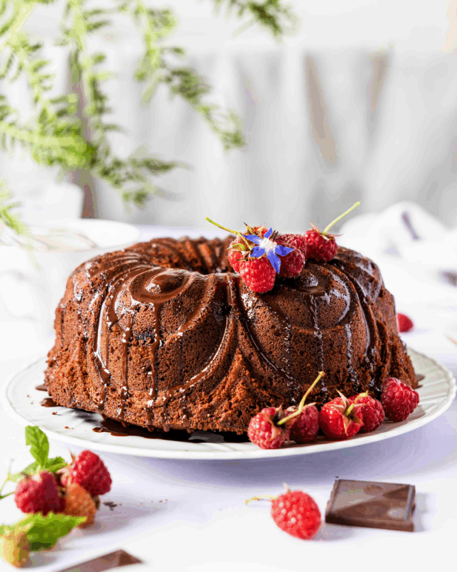 Schokoladiger Bundt Cake mit flüssigem Schoko-Topping und frischen Himbeeren.