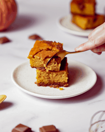 Zwei Stückchen Schoko-Kürbis-Brownies übereinander werden mit einem Löffel zerteilt.