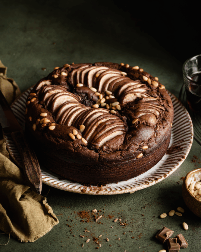 Schokoladen-Birnen-Kuchen mit Pinienkernen bestreut.
