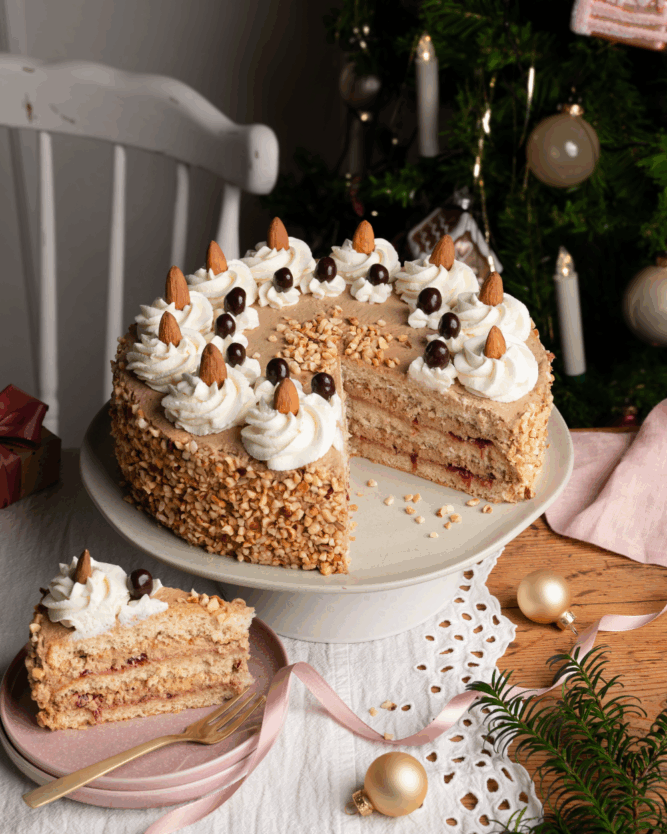 Festliche Torte mit mehreren Schichten, Schokoladencreme, Sahne und Dekorationen in weihnachtlichem Tischambiente.