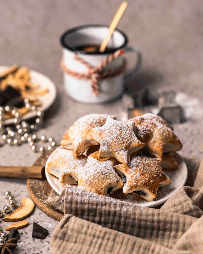Gefüllte Glühwein-Schoko-Sterne mit einer Tasse Glühwein und weihnachtlicher Dekoration.
