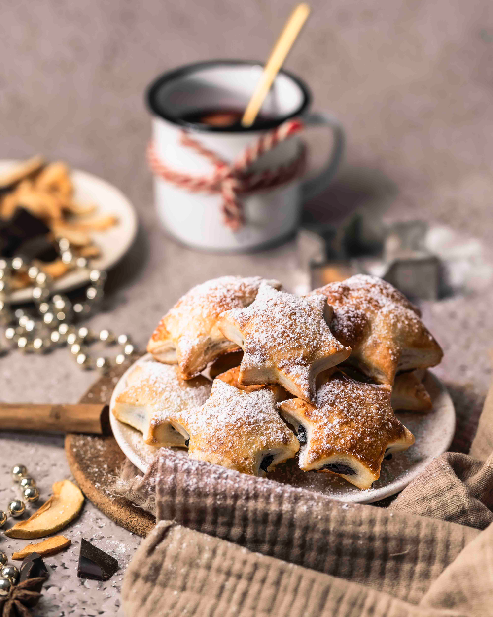 Gefüllte Glühwein-Schoko-Sterne mit einer Tasse Glühwein und weihnachtlicher Dekoration.