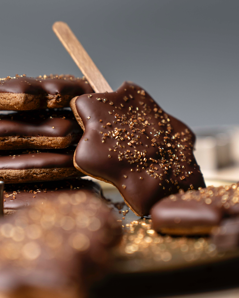 Schokolierte Lebkuchen am Stiel mit goldenem Streuseldekor.
