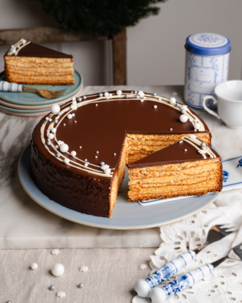 Baumkuchen mit Bitterschokoladenglasur und weißer Schokoladendekoration.