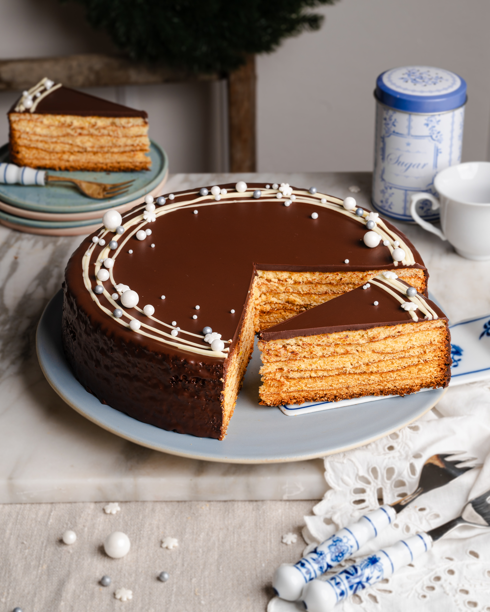 Baumkuchen mit Bitterschokoladenglasur und weißer Schokoladendekoration.