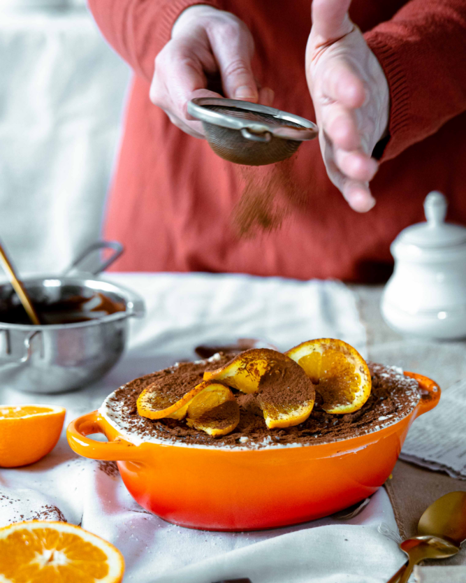 Ein Schoko-Orangen-Tiramisu mit frischen Orangen wird mit Kakaopulver bestäubt.