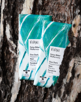 feine-bitter-pfefferminz-vivani-bio-schokolade Zwei Tafeln Feine Bitter Pfefferminz von VIVANI Bio-Schokolade vor einem Stück Baumrinde.