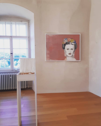 Exhibition space featuring a painting of Frida Kahlo by Ute Drescher.