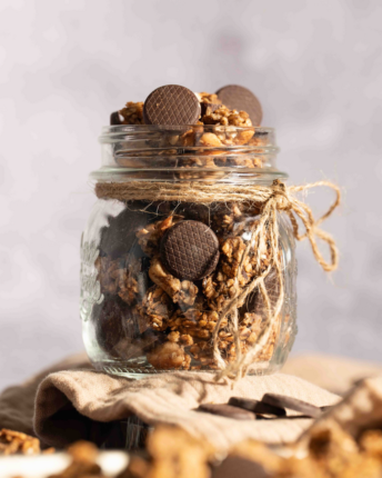 Ein offenes Vorratsglas mit Granola, verfeinert mit Schokoladentalern.