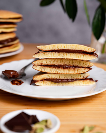 dorayaki-mit-schokofuellung-vivani Ein Teller mit drei aufgeschnittenen, japanischen Pfannkuchen Dorayaki mit Schokoladenfüllung.